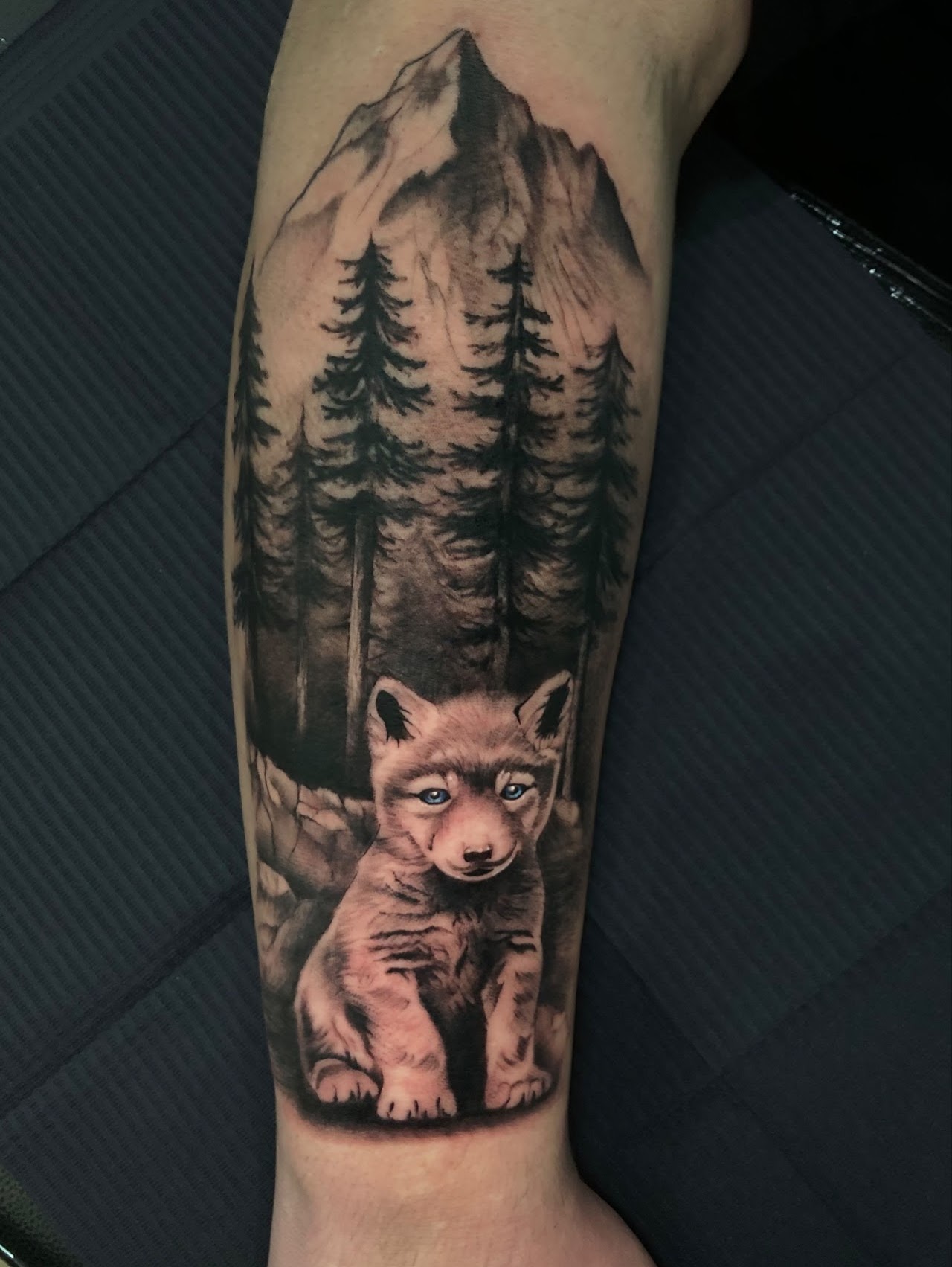 Tatuaje lobo cachorro bosque montaña — CAOS Art Tattoo Chile