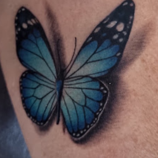 Tatuaje mariposa azul realismo color — CAOS Art Tattoo Chile