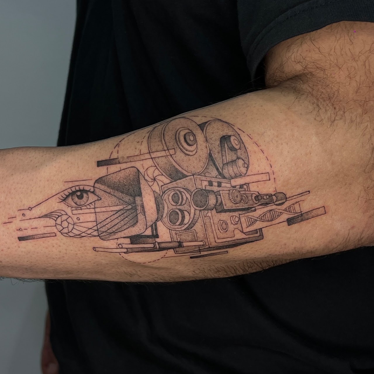 Tatuaje Cámara de cine mecánica lineal con ojo y ADN — CAOS Art Tattoo Chile