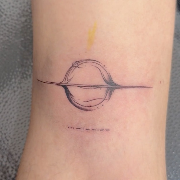 Tatuaje Planeta con anillo minimalista lineal — CAOS Art Tattoo Chile
