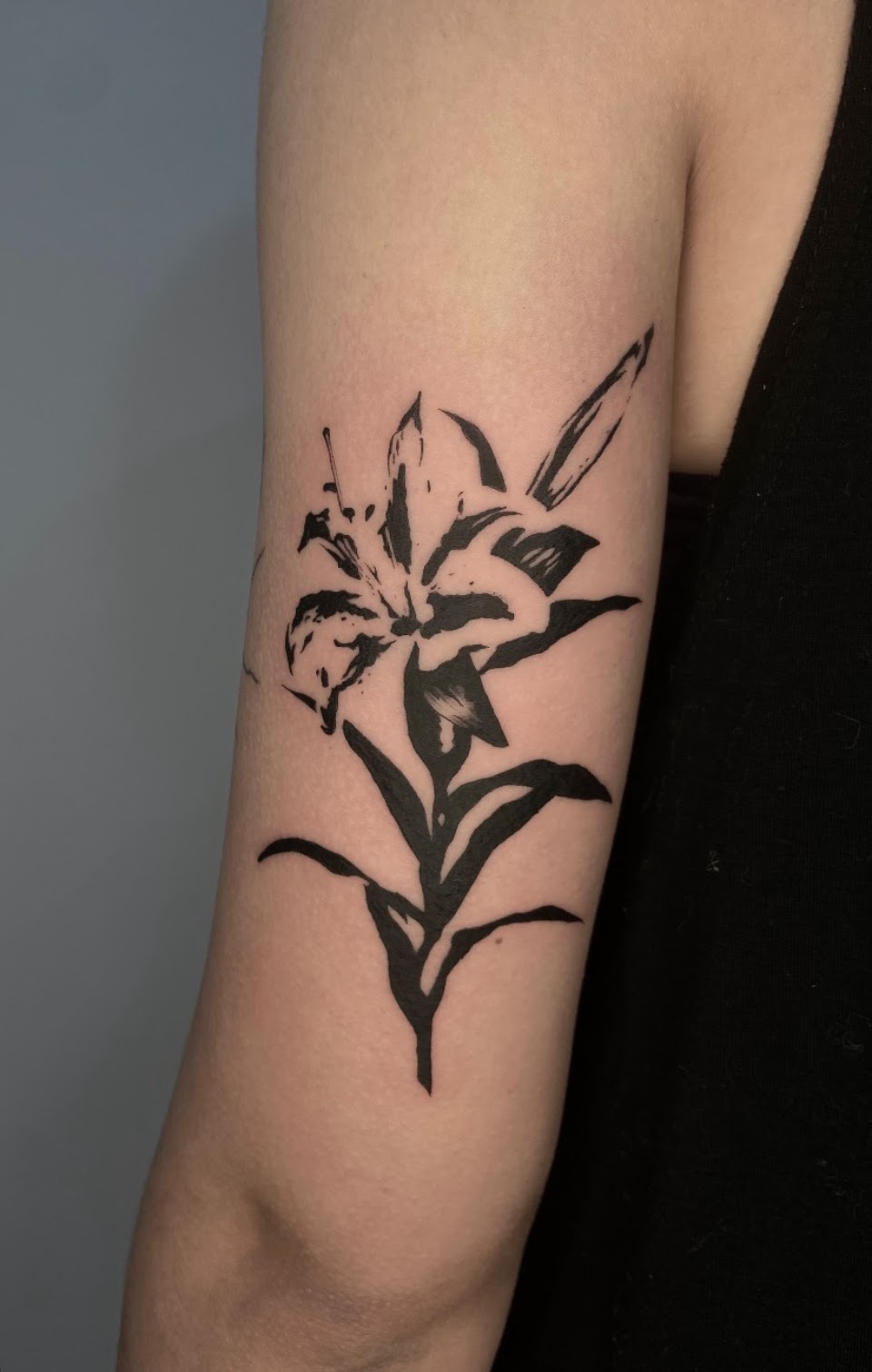 Tatuaje Lirio blackwork pincelada expresiva — CAOS Art Tattoo Chile
