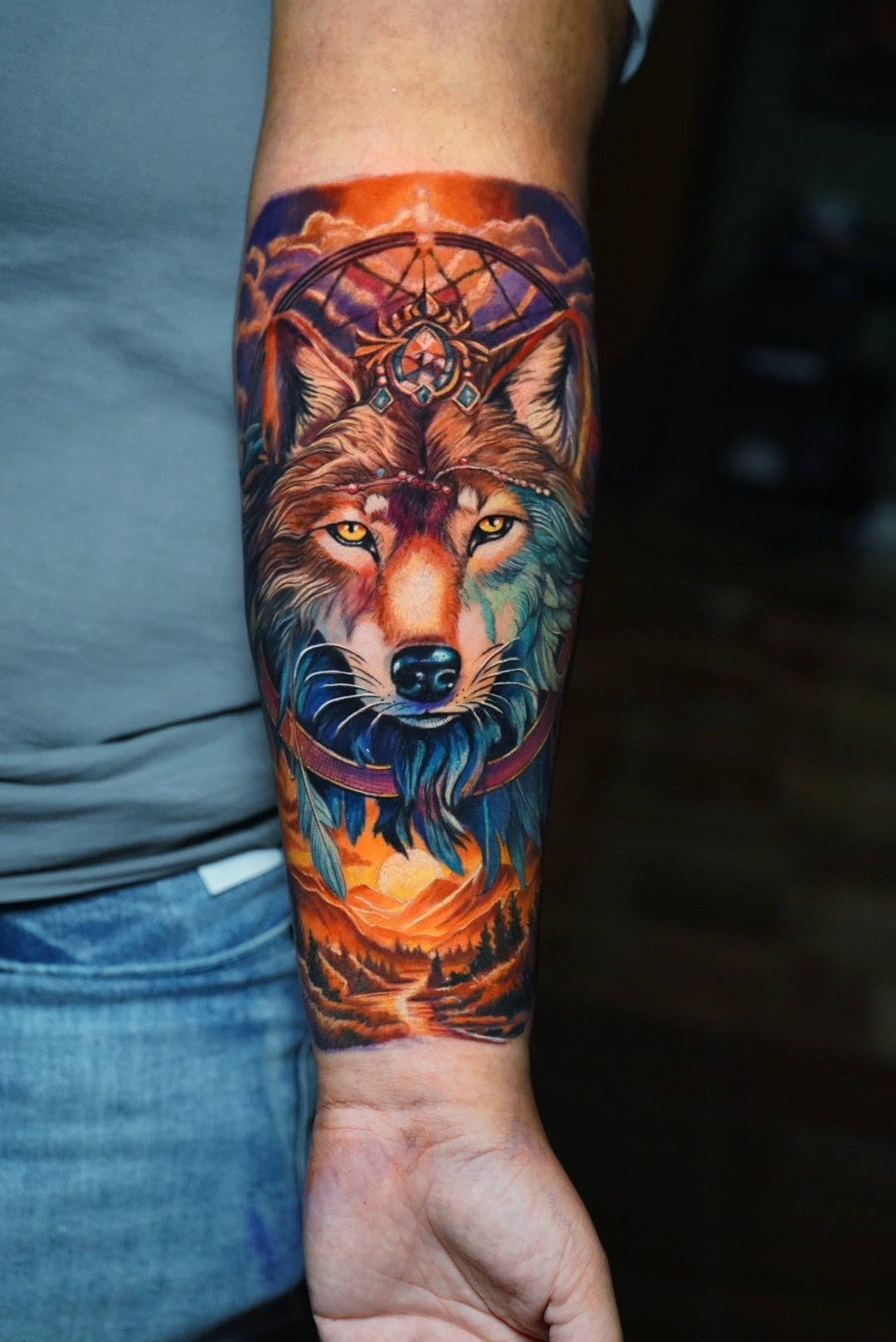 Tatuaje Lobo a color con atrapasueños y paisaje cósmico — CAOS Art Tattoo Chile