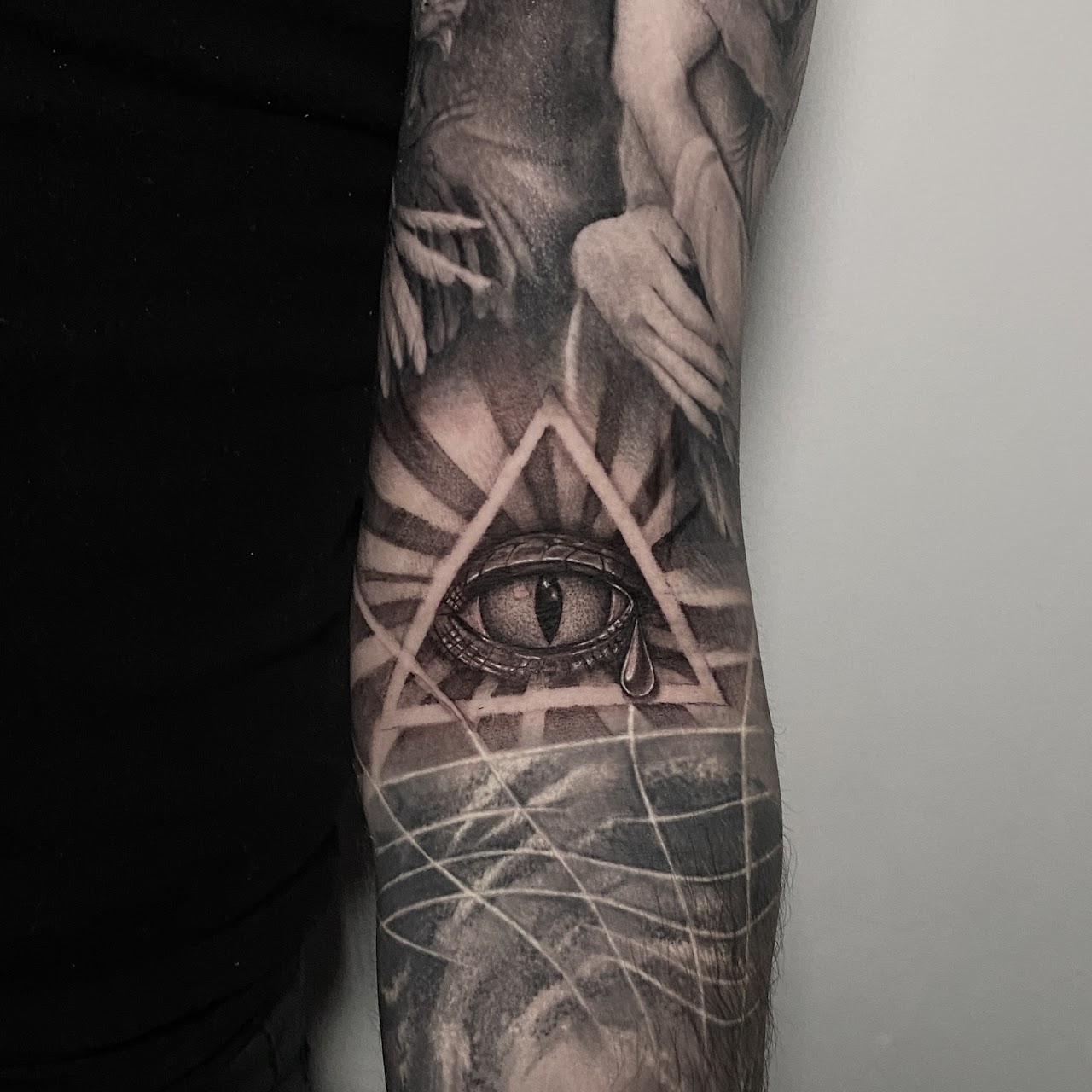 Tatuaje ojo que todo lo ve triángulo en mano blackwork — CAOS Art Tattoo Chile