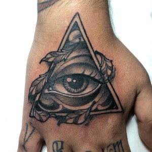 Tatuaje ojo realista con mandala y plumas dotwork — CAOS Art Tattoo Chile