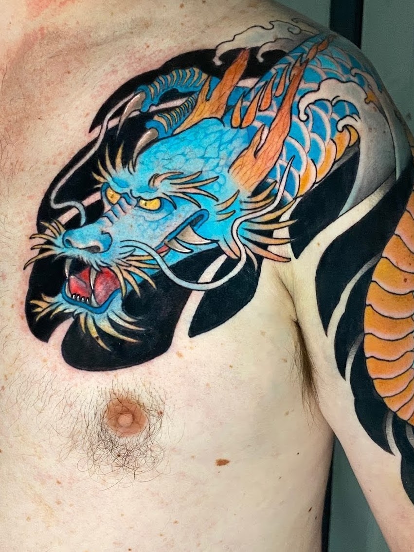Tatuaje dragón azul con llamas en pecho neo japonés — CAOS Art Tattoo Chile