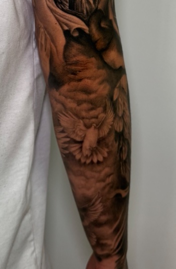 Antebrazo con palomas y cruces — tatuaje realismo — CAOS Art Tattoo Chile