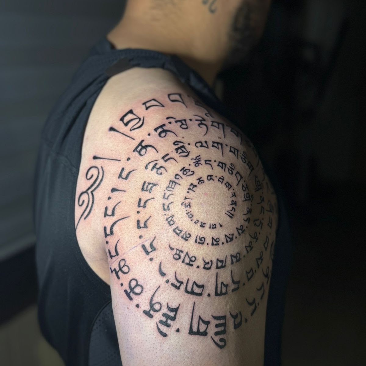 Tibetan spiral script tattoo by Caos Art Tattoo Santiago